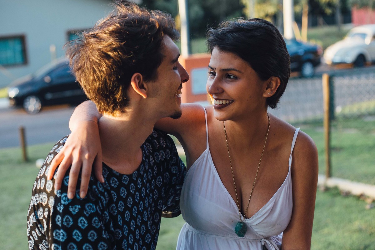 Casal se olhando e sorrindo no por do sol
