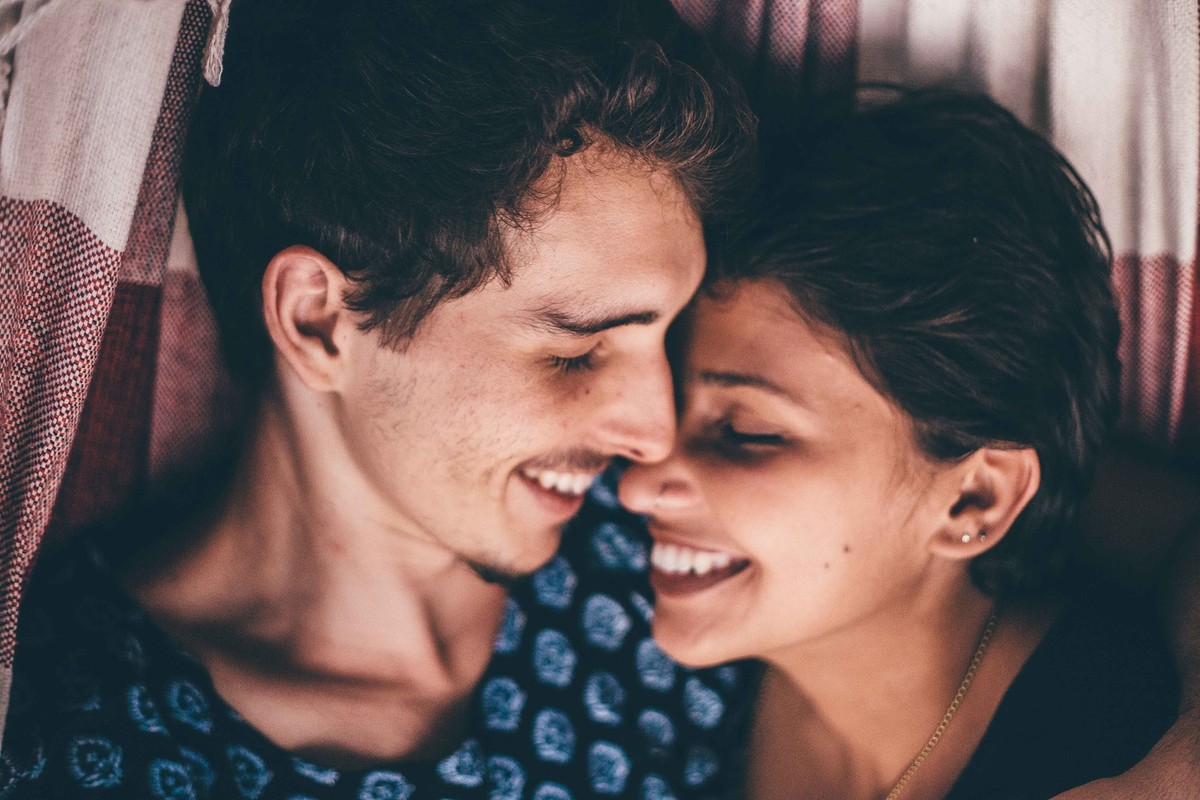 foto de casal apaixonados deitados na rede e olhando um para o outro