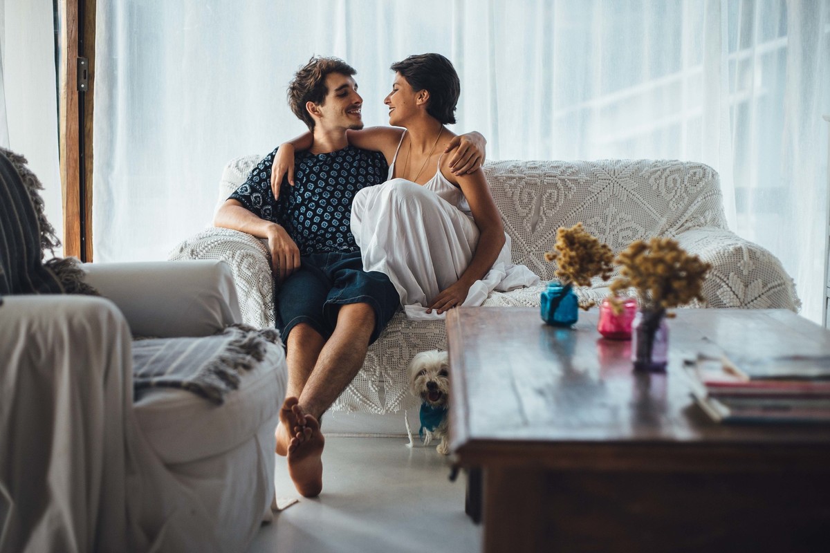 Ensaio de casal em casa, sentados no sofa com um cachorrinho