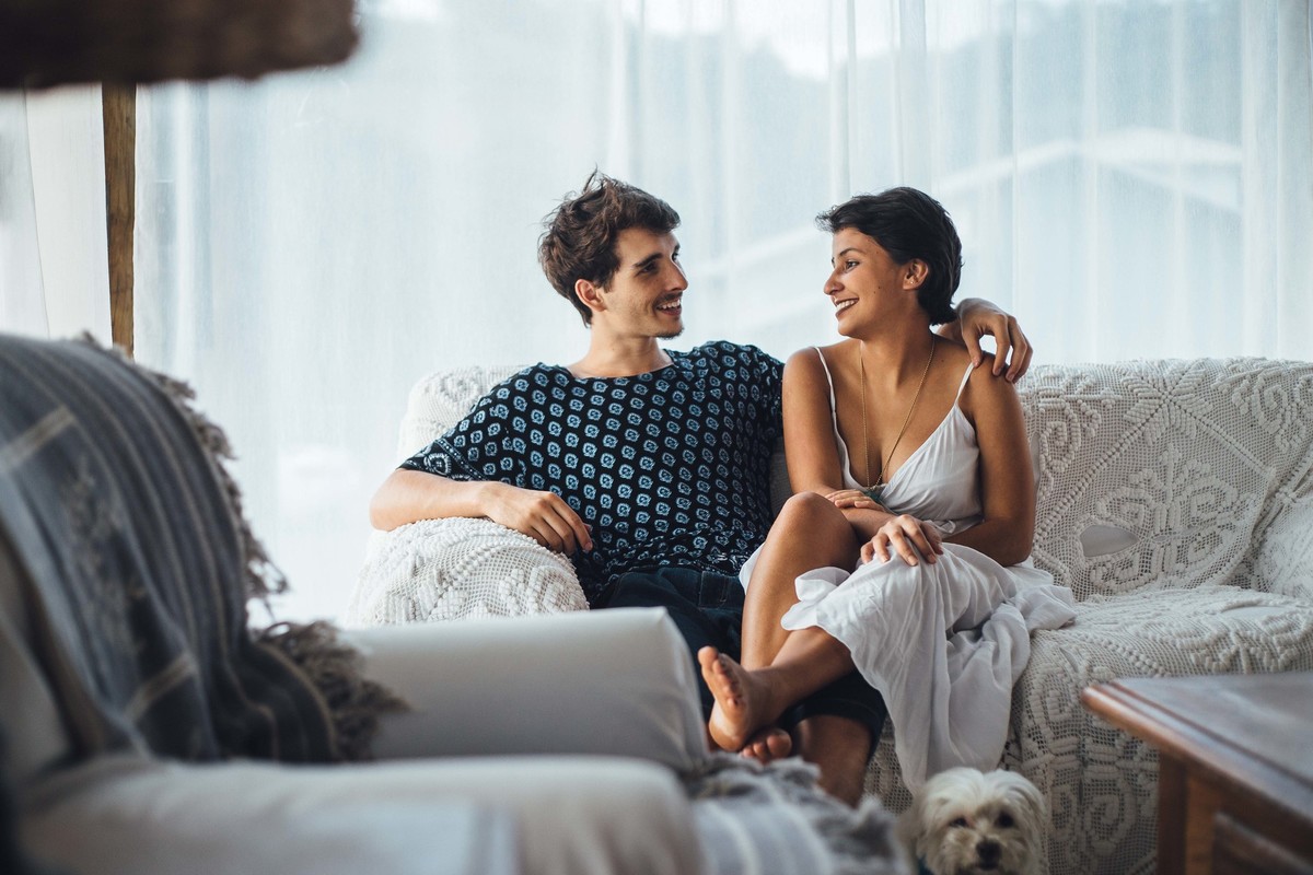 Ensaio de casal em casa, sentados no sofa com um cachorrinho