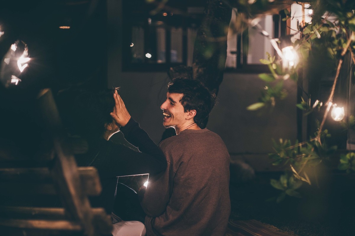 Foto de casal a noite com varal de luz, casal se olhando e rindo