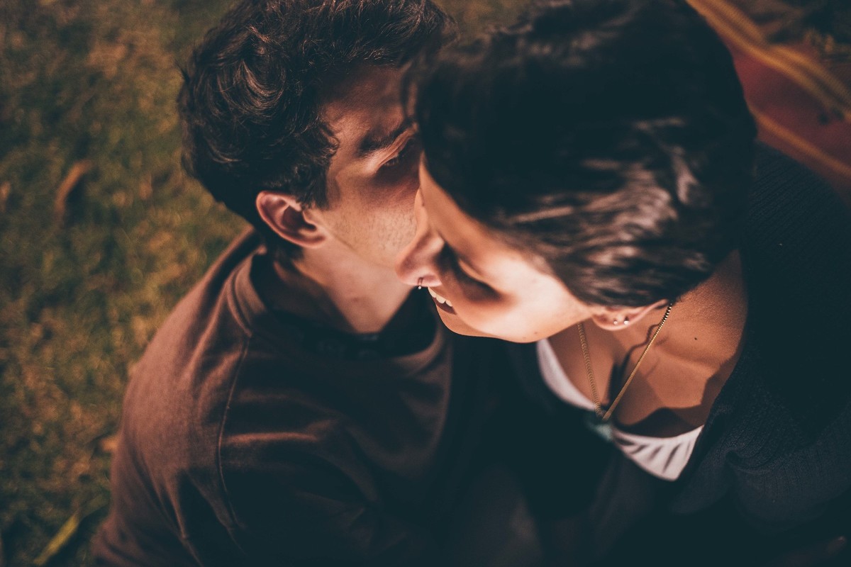 Foto de casal a noite com varal de luz, casal fazendo carinho um no outro e sorrindo