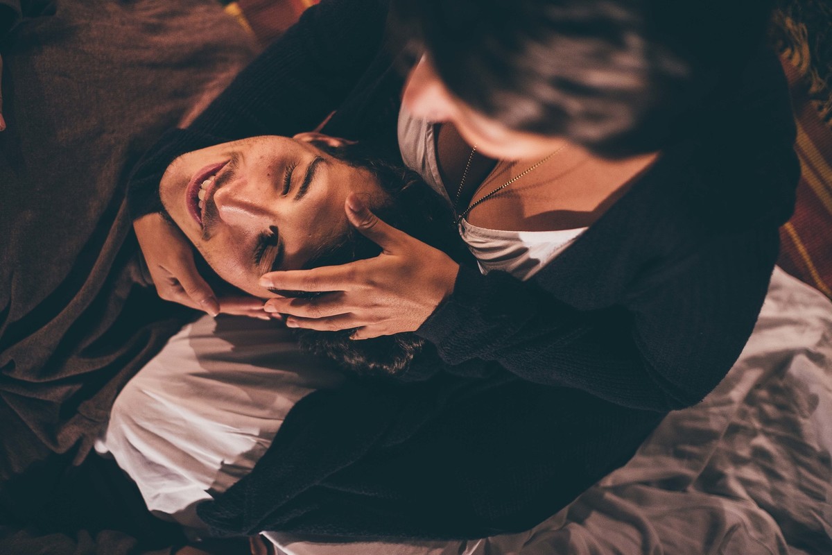 Foto de casal a noite com varal de luz, casal fazendo carinho um no outro e sorrindo