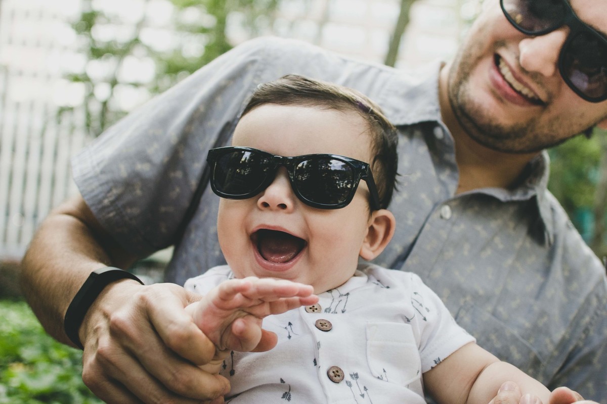 Ensaio fotográfico de família em Nova York, pai e filho com óculos escuro sorrindo, pai segurando filho no colo