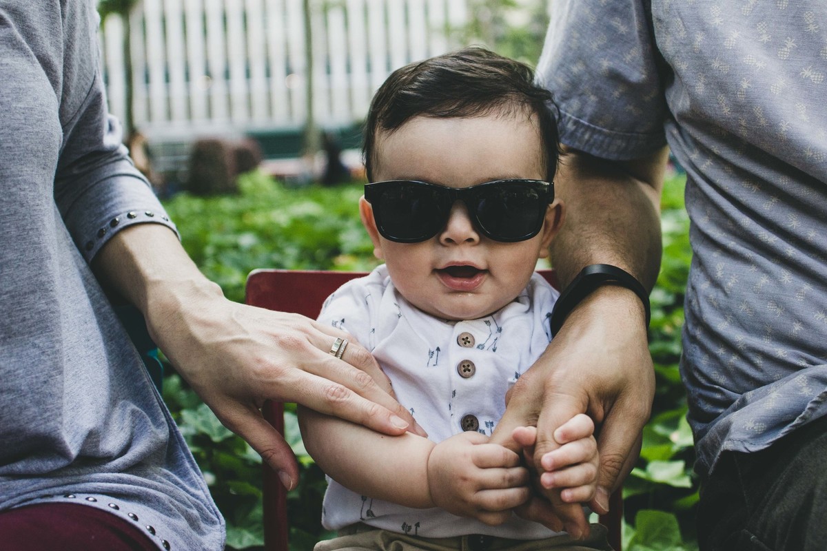 Ensaio fotográfico de família em Nova York, pai e mãe sentados ao lado do filho que posa e sorri para a foto