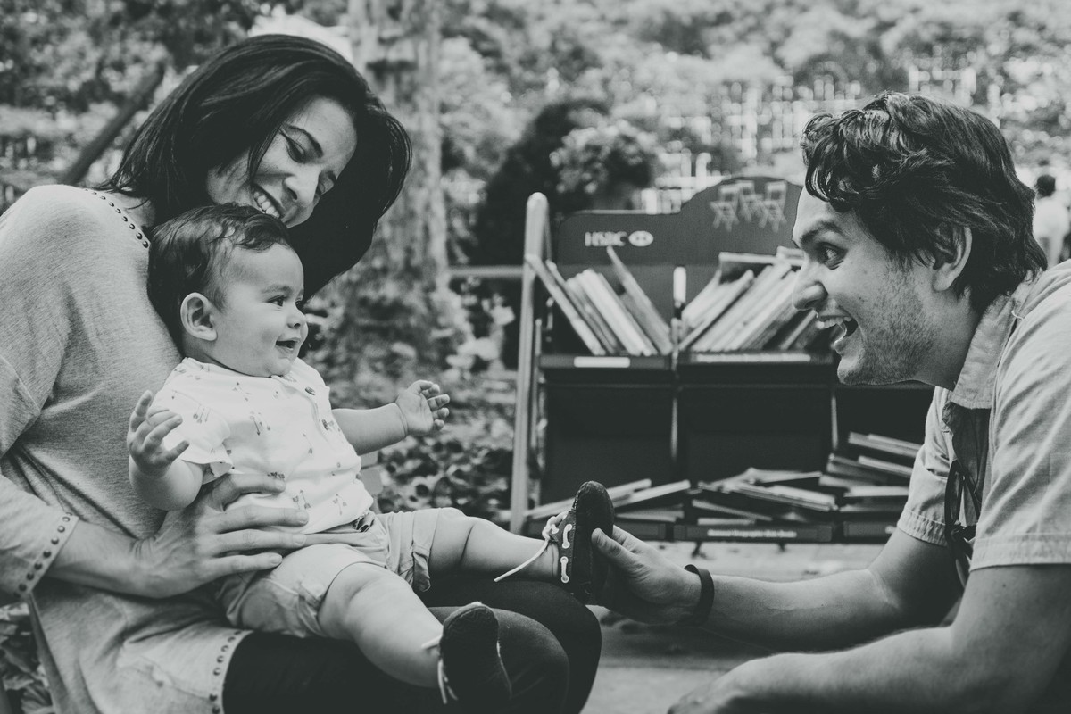 Ensaio fotográfico de família em Nova York, criança sentada no colo da mãe, pai agachado na frente sorri para filho, filho sorri para o pai, foto preto e branco