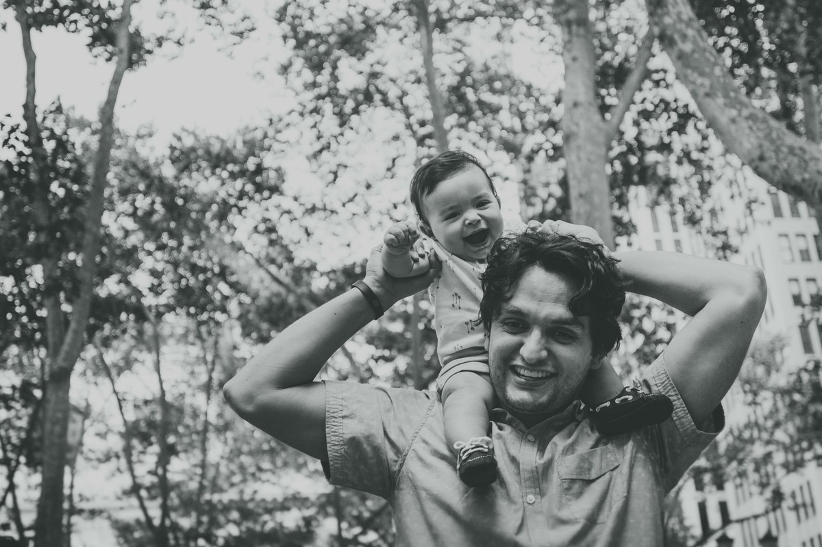 Ensaio fotográfico de família em Nova York, pai segura filho nos ombros, filho sorri, foto preto e branco
