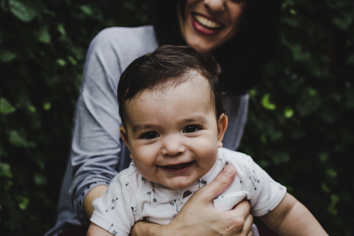 Ensaio fotográfico de família em Nova York, mãe segura filho, filho posa para a câmera e sorri