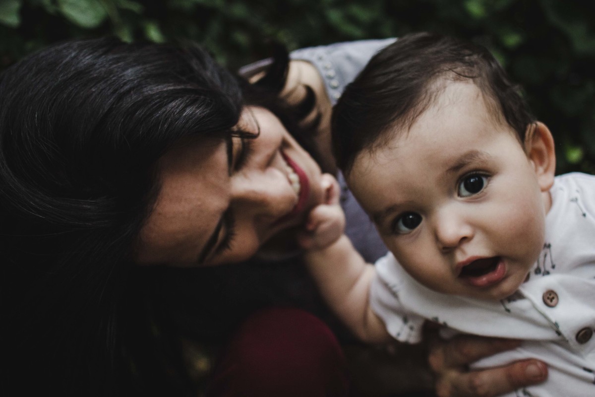 Ensaio fotográfico de família em Nova York, mãe olha para filho que olha para a câmera curioso