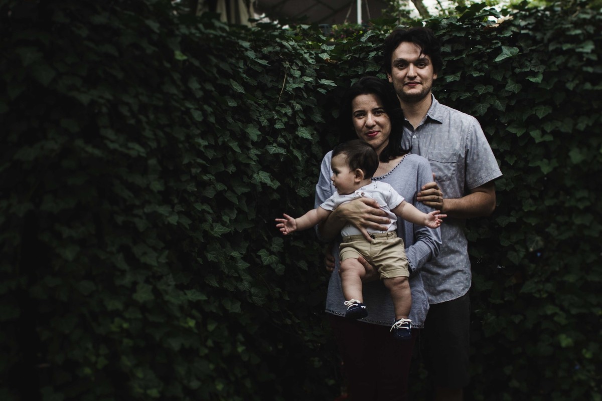 Ensaio fotográfico de família em Nova York, mãe segura filho no colo, pai abraça esposa, criança olha para o lado