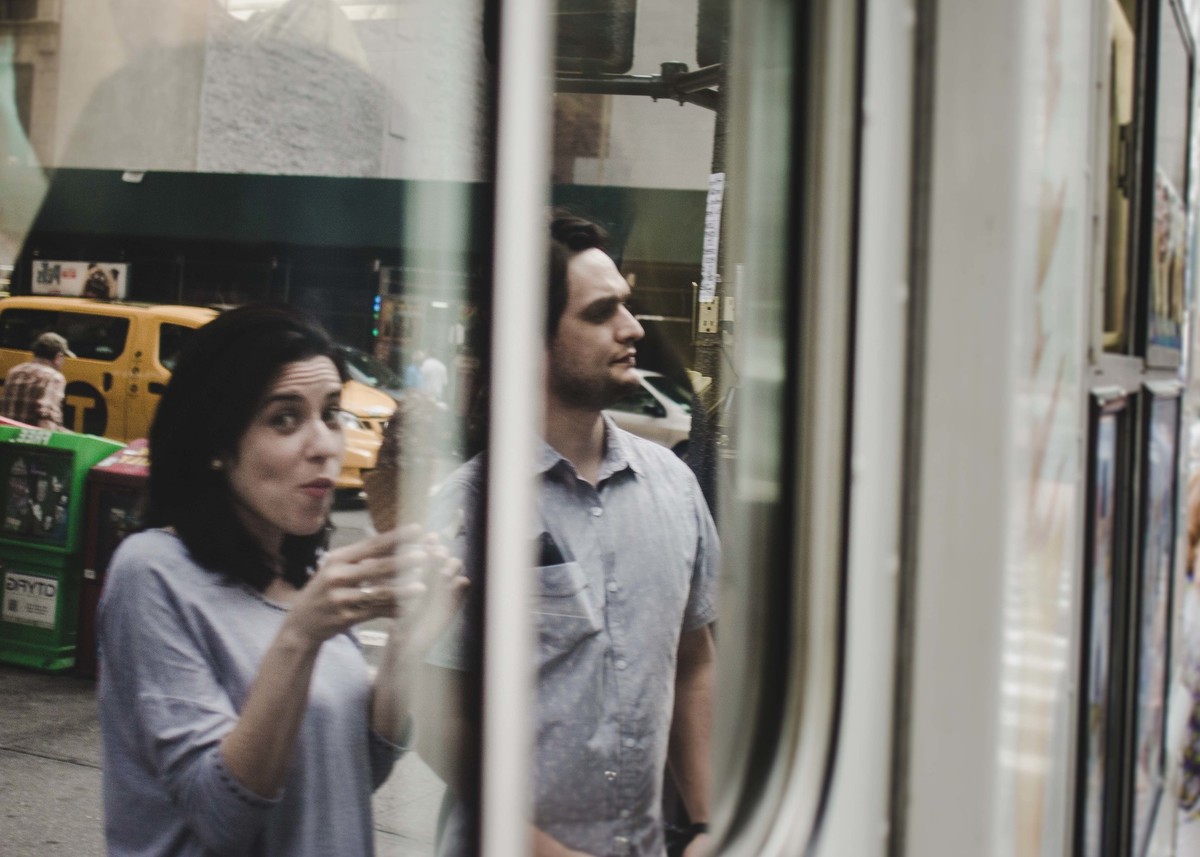 Ensaio fotográfico de família em Nova York, reflexo de pai e mãe comprando sorvete em um caminhão, eles estão em uma calçada de uma cidade grande
