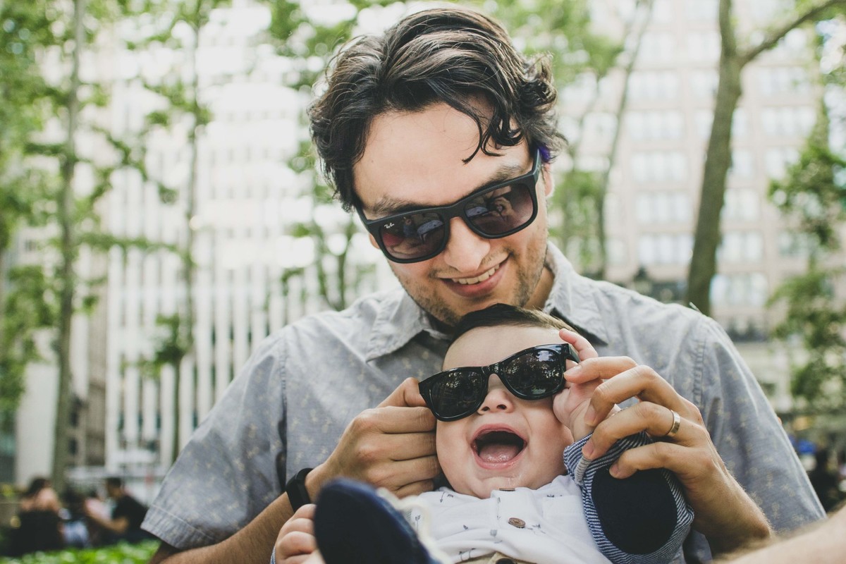 Ensaio fotográfico de família em Nova York, pai e filho com óculos escuro sorrindo, pai segurando filho no colo