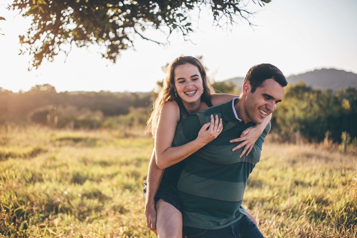 fotografia de casal no por do sol, noiva indo de cavalinho no noivo e sorrindo, ensaio de casal divertido e descontraido