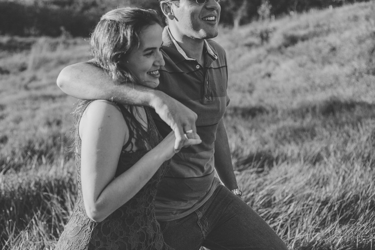 Foto em Preto e Branco de casal abraçados e sorrindo caminhando no campo