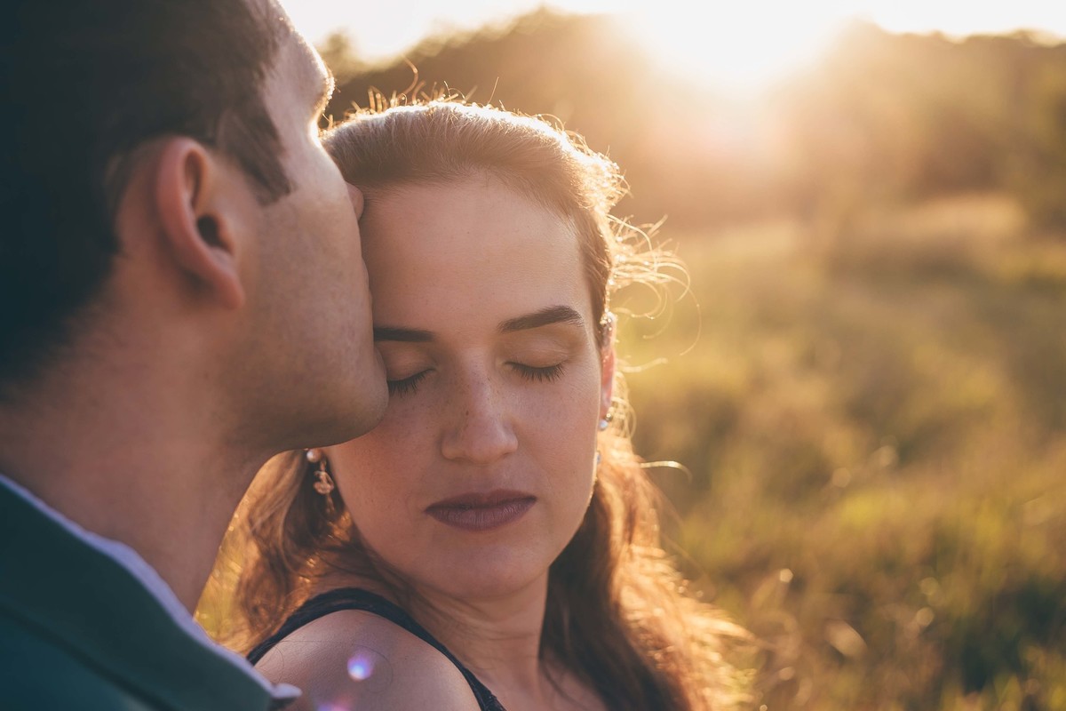 noivo beijando a testa da noiva no por do sol