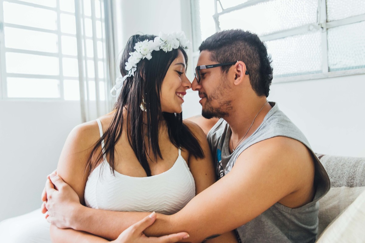 gestante moderna sentada no sofá com o marido