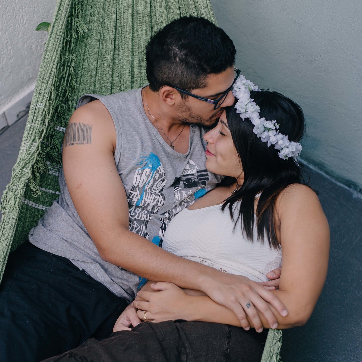 casal deitado na rede e beijando a testa da esposa durante um ensaio de gestante em Belo Horizonte