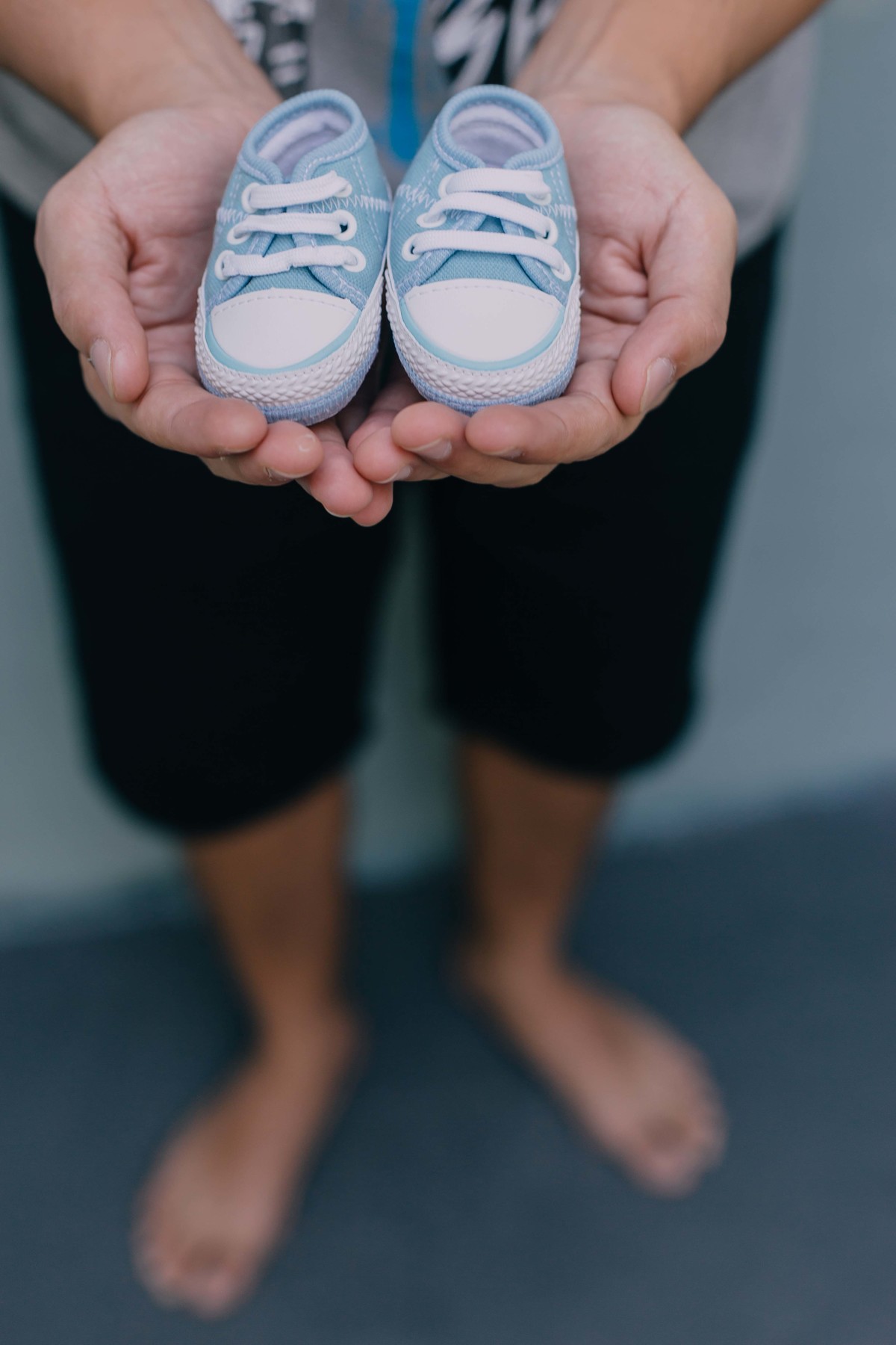 pai segurando sapatinhos de recém nascido nas mãos