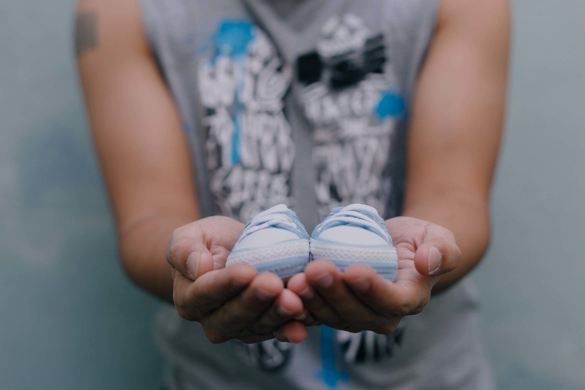 pai segurando sapatinho de recém nascido nas mãos