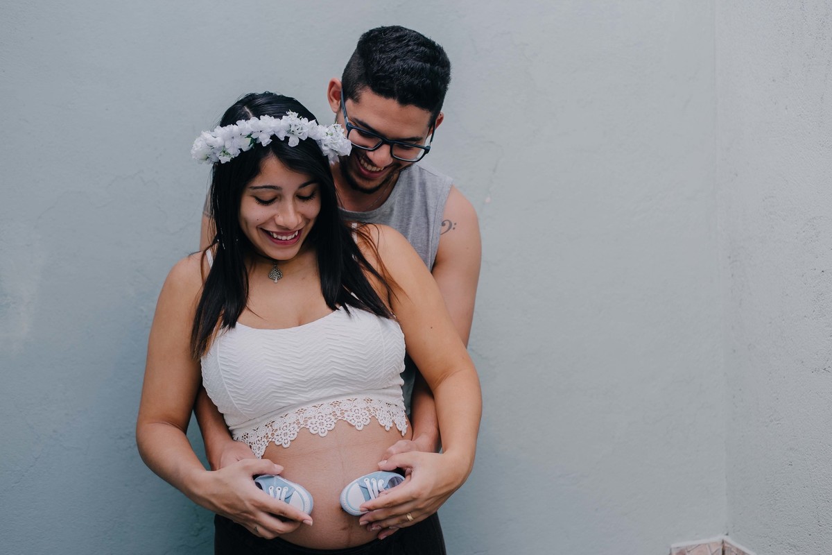 casal abraçado e brincando com a barriga de gestante da esposa