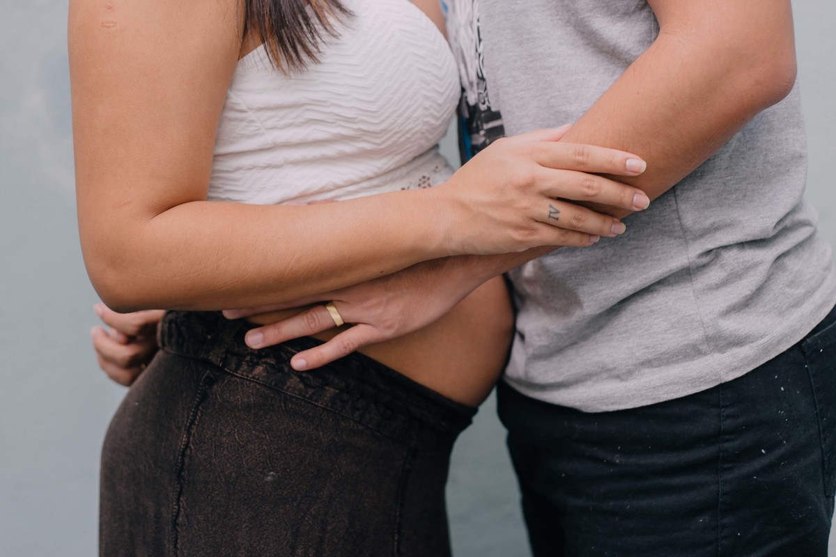 detalhes das mãos com alianças e tatuagens