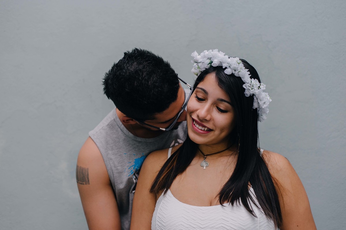 marido beijando o pescoço da esposa que está sorrindo