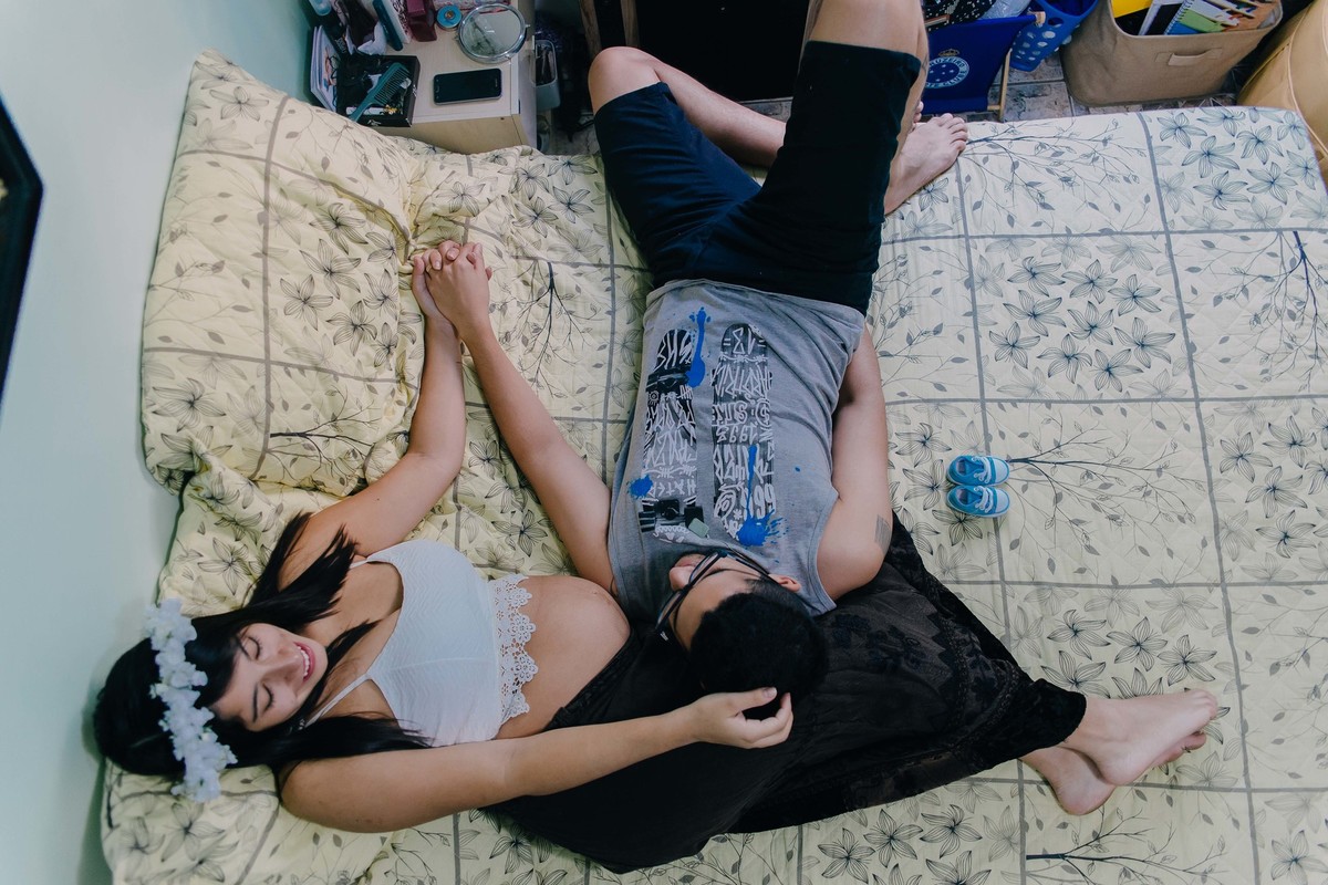 casal deitado no colo um do outro na cama