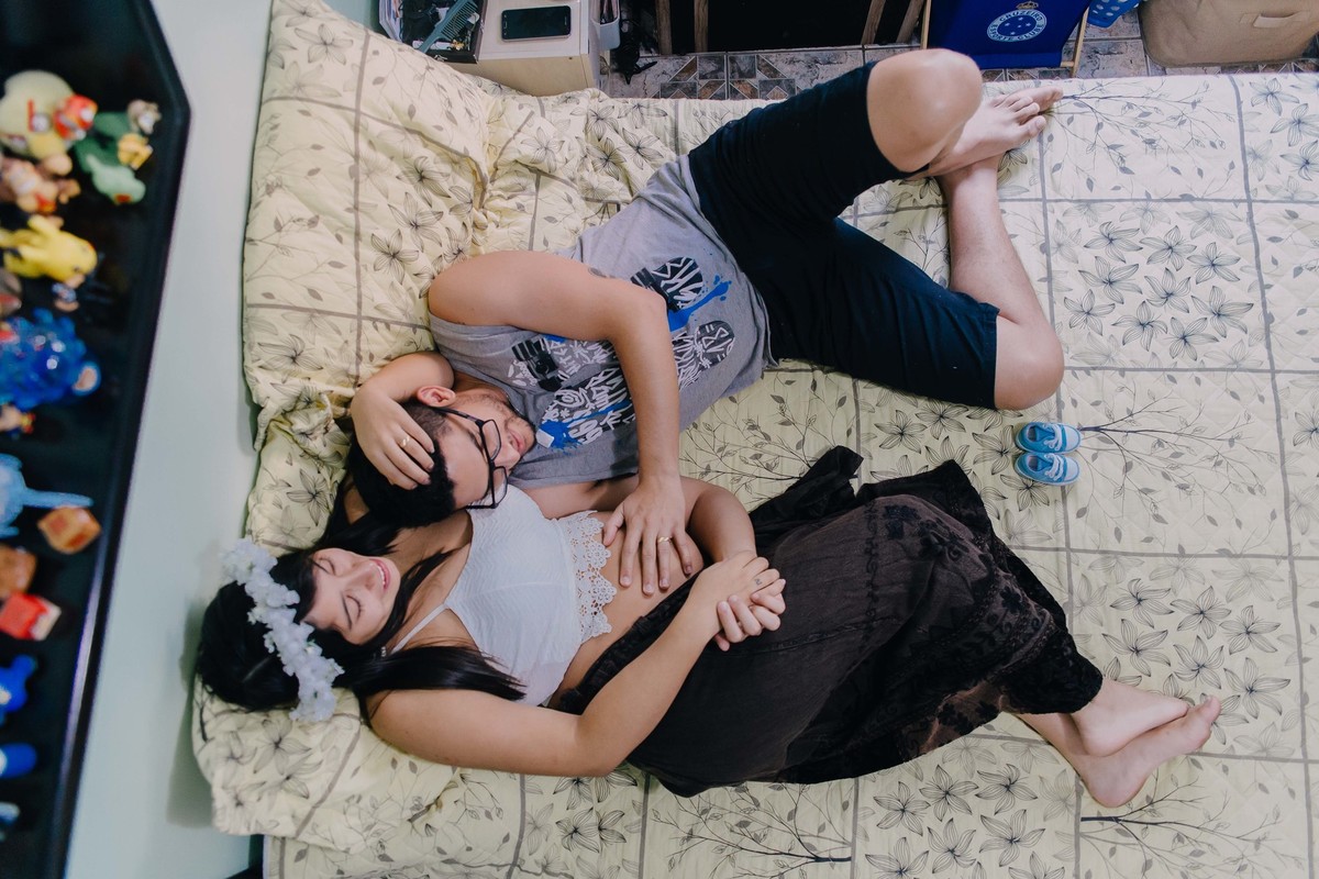 casal deitado na cama e fazendo carinho um no outro, pai fazendo carinho na barriga da esposa gravida