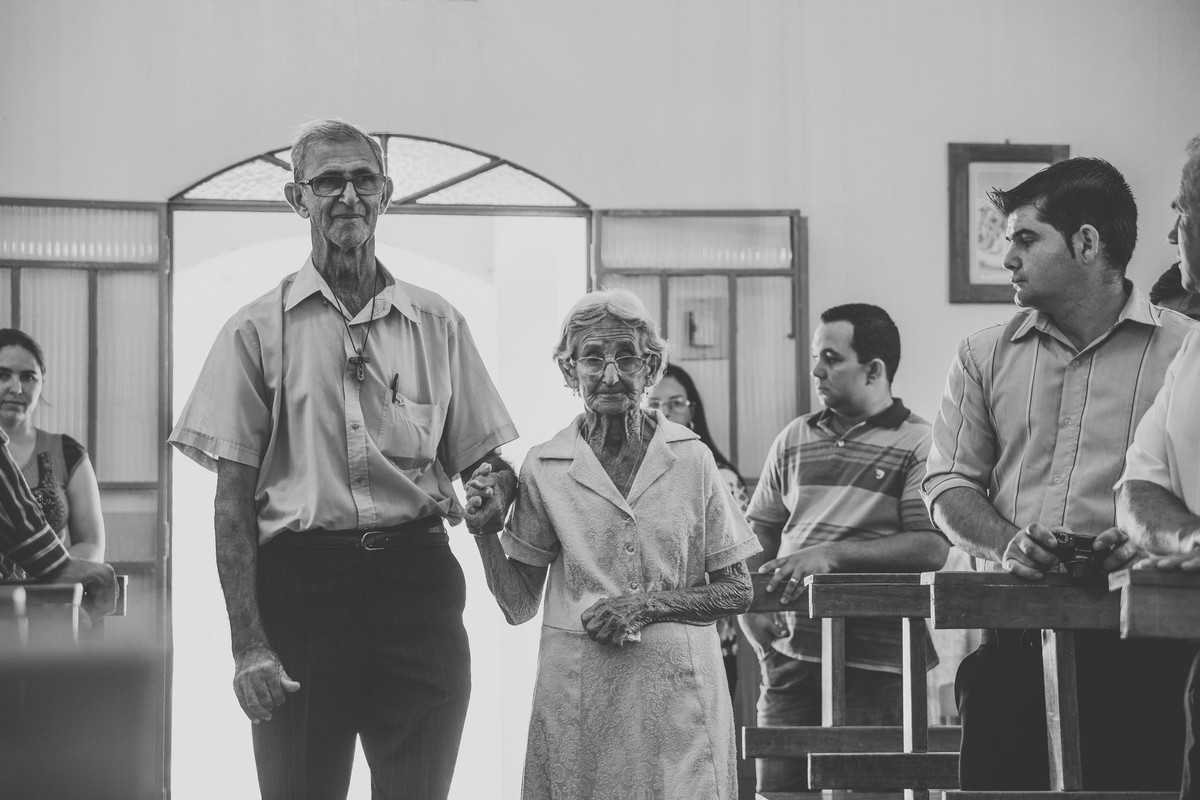 Dona marieta entrando na igreja de mãos dadas com o filho e o Fotografo de casamento registrando com muita sensibilidade todos os momentos