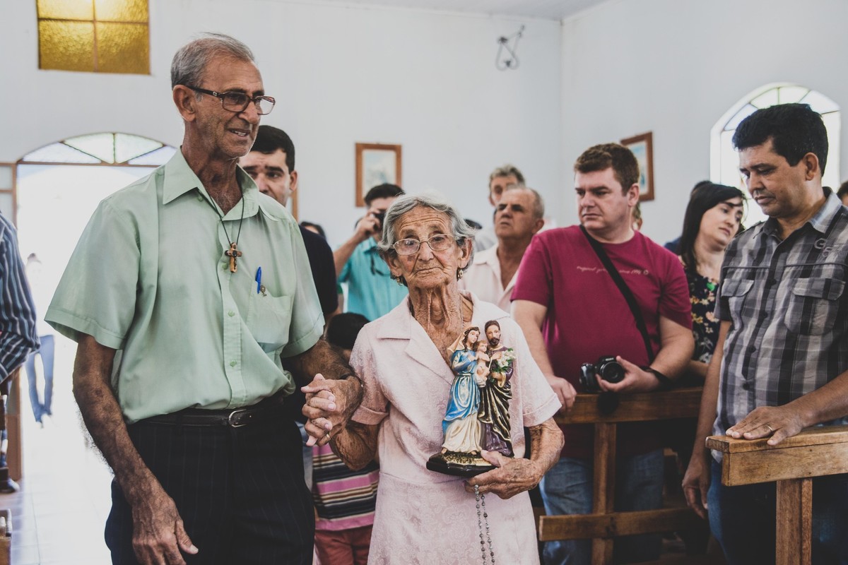 Senhora segurando uma imagem de Nossa senhora nos braços de mãos dadas com o filho