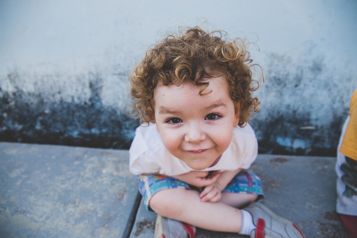 Criança de cabelos cacheados como um anjinho sorrindo para a foto