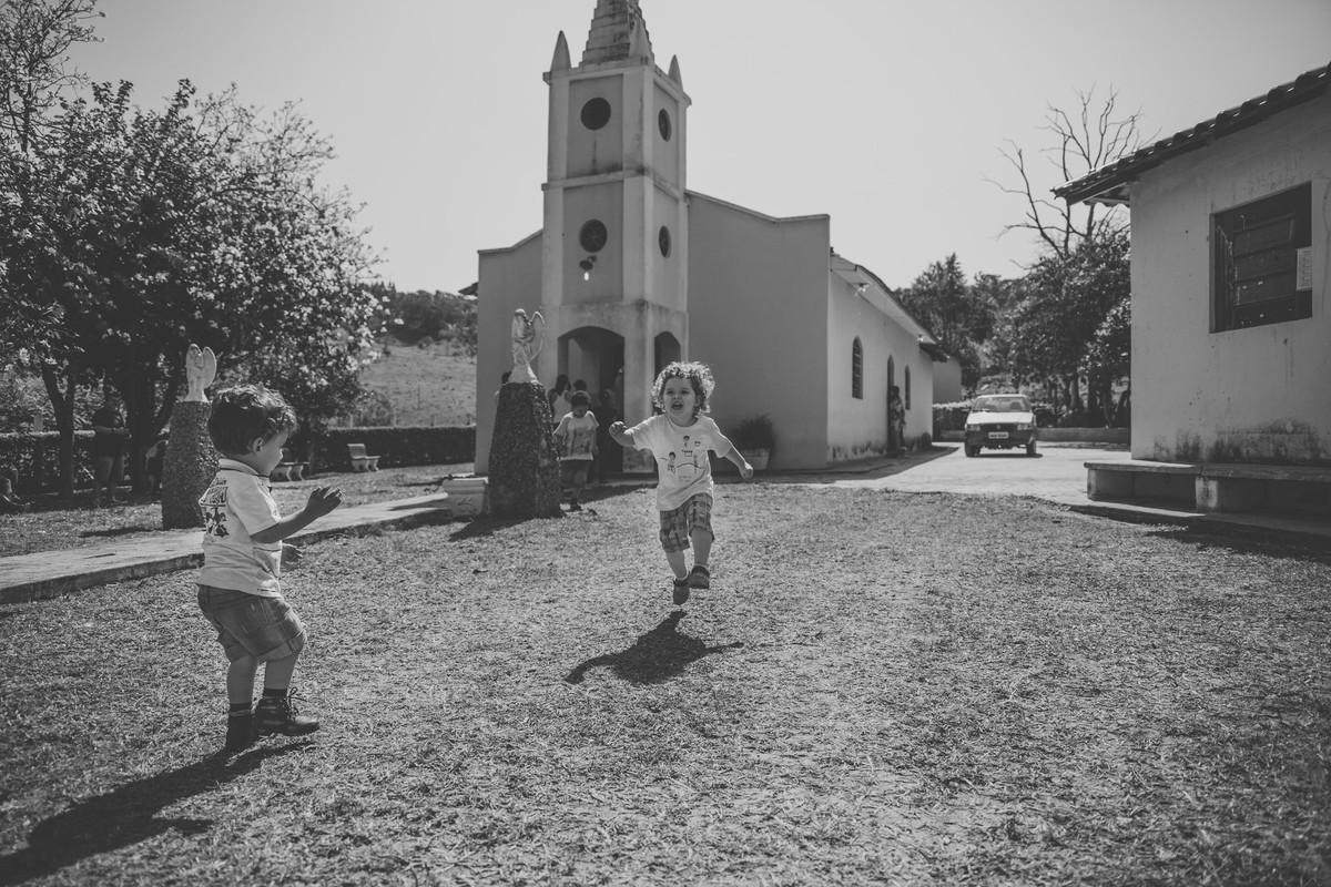 Criança pulando na frente da igreja e foi dificil para o fotografo de casamentos acompanhar o pique