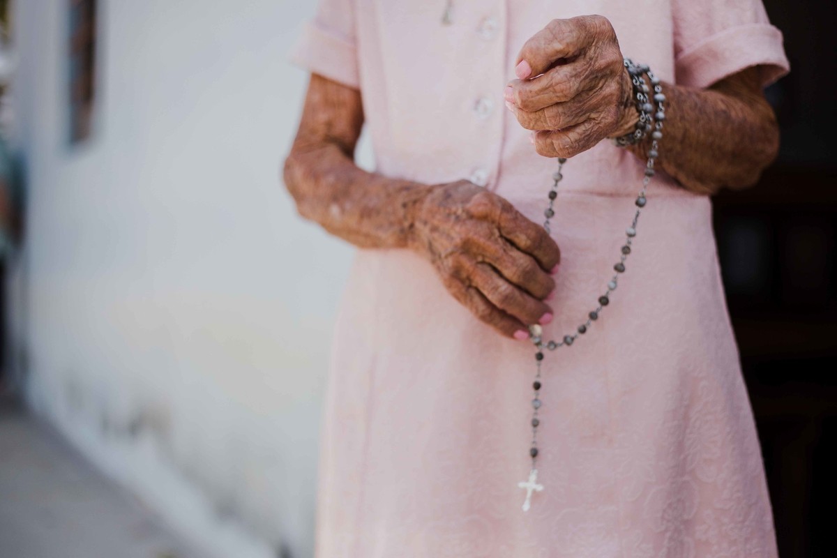 senhora de fé segurando o terço