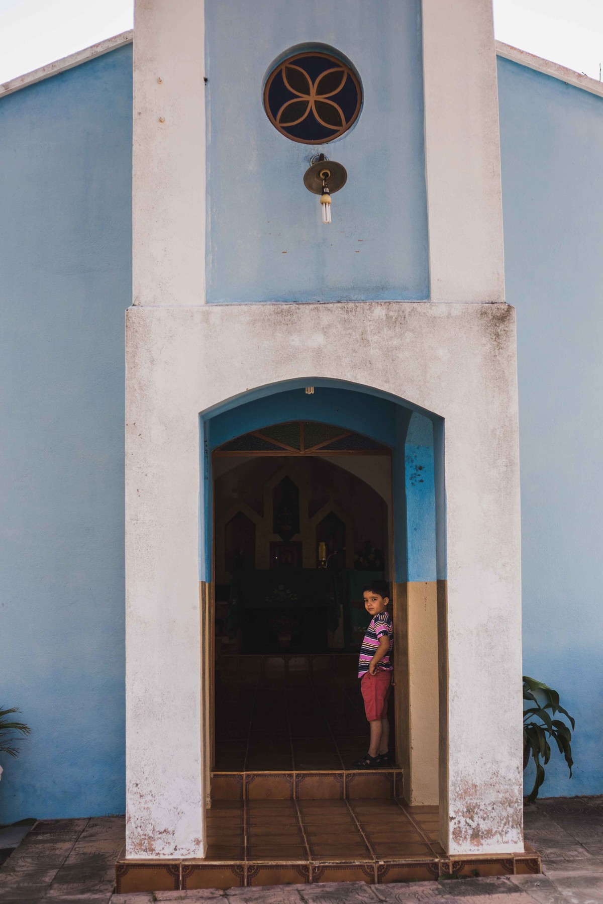 criança escorada na porta da igreja