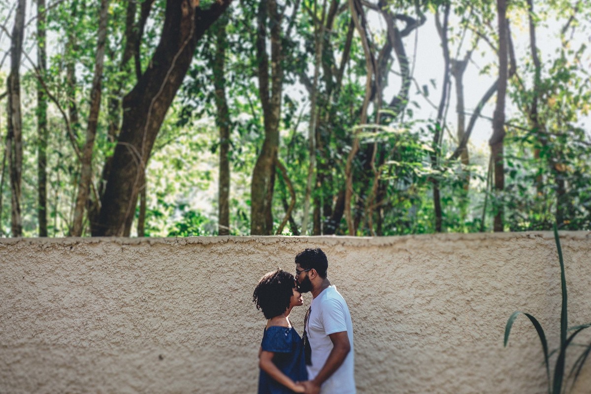 Ensaio de pré casamento em que o noivo está beijando a testa da noiva e segurando as mãos dela