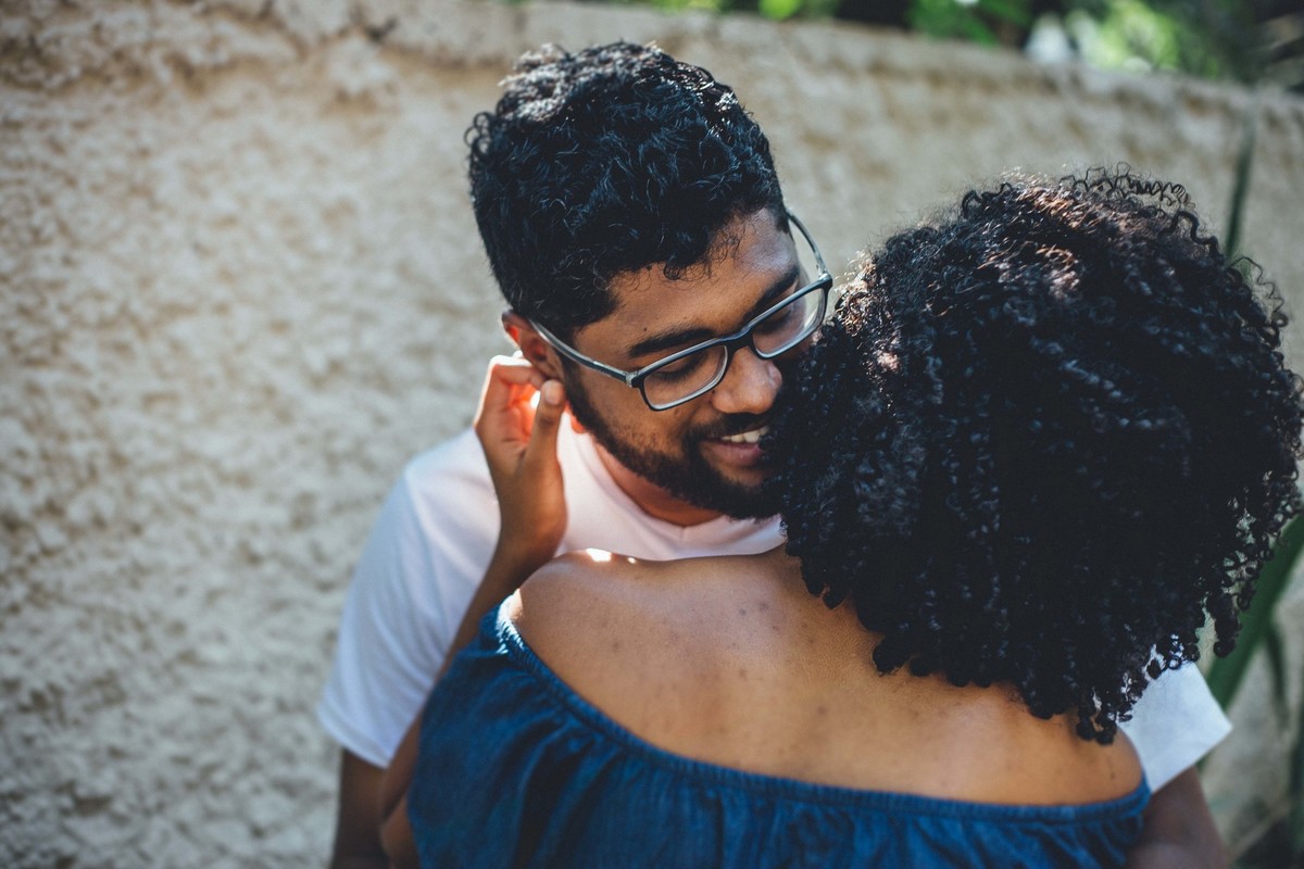 Noivo sorrindo enquanto cheira o pescoço da noiva