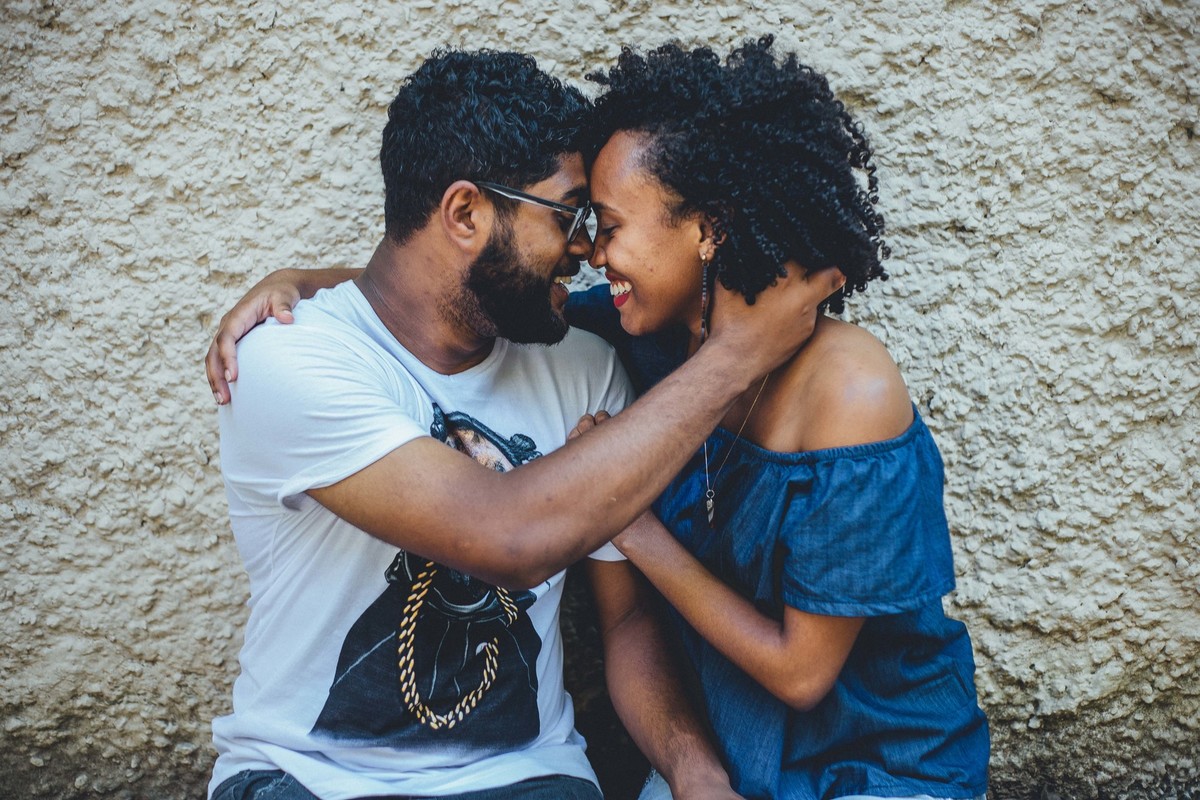Noivos sorrindo e olhando um para o outro com a cabeça colada e os braços entrelaçados sorrindo