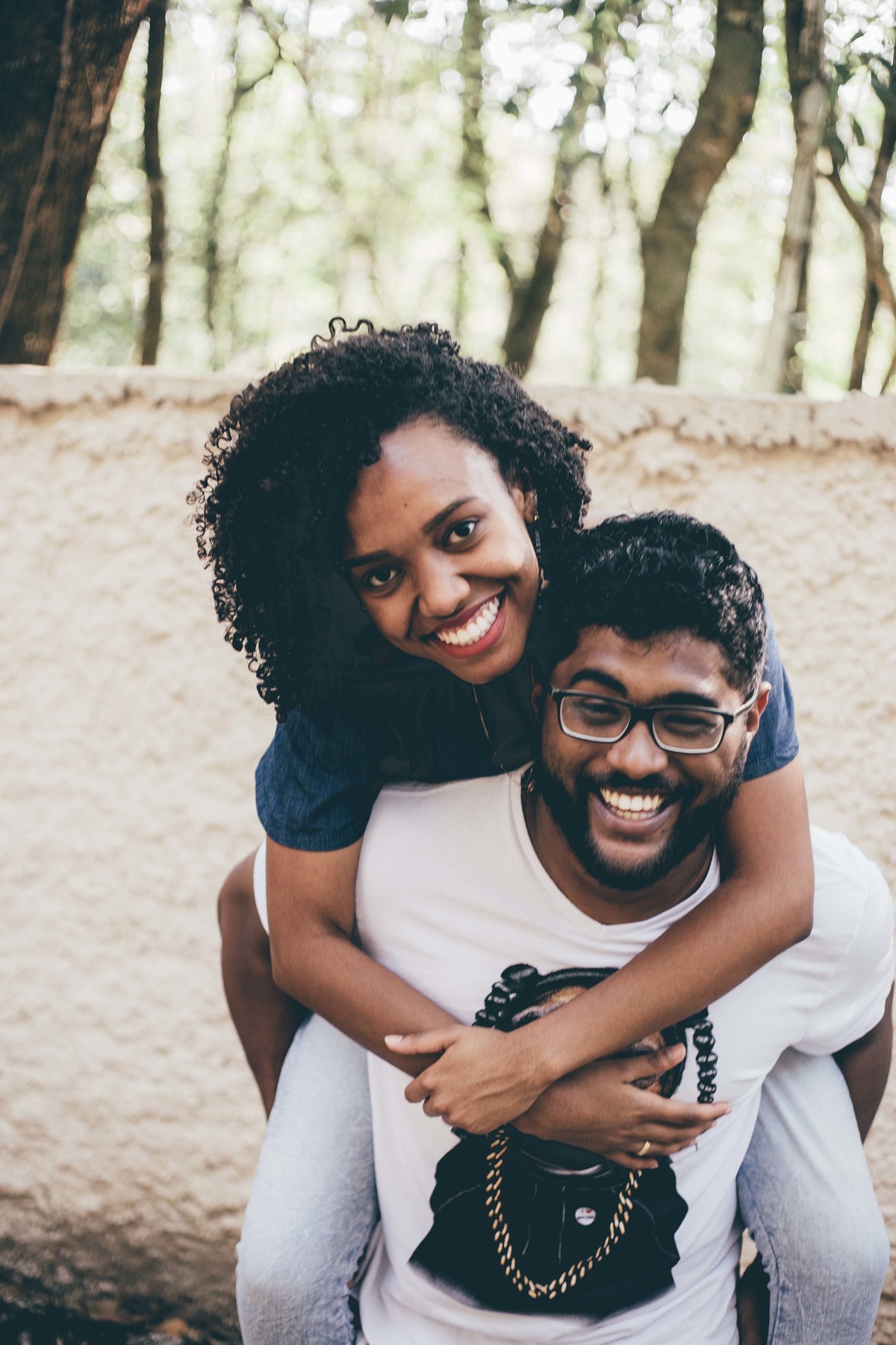 Noivo carregando a noiva de cavalinho e sorrindo olhando para a câmera