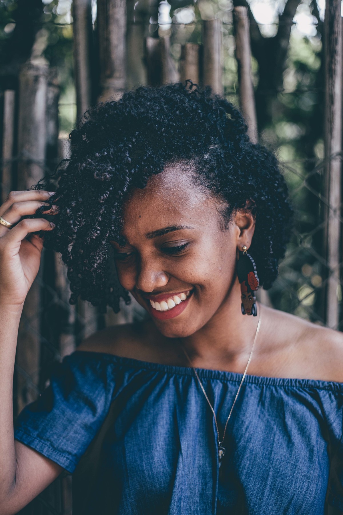retrato feminino em que a modelo sorri para a foto e tem um belo cabelo cacheado
