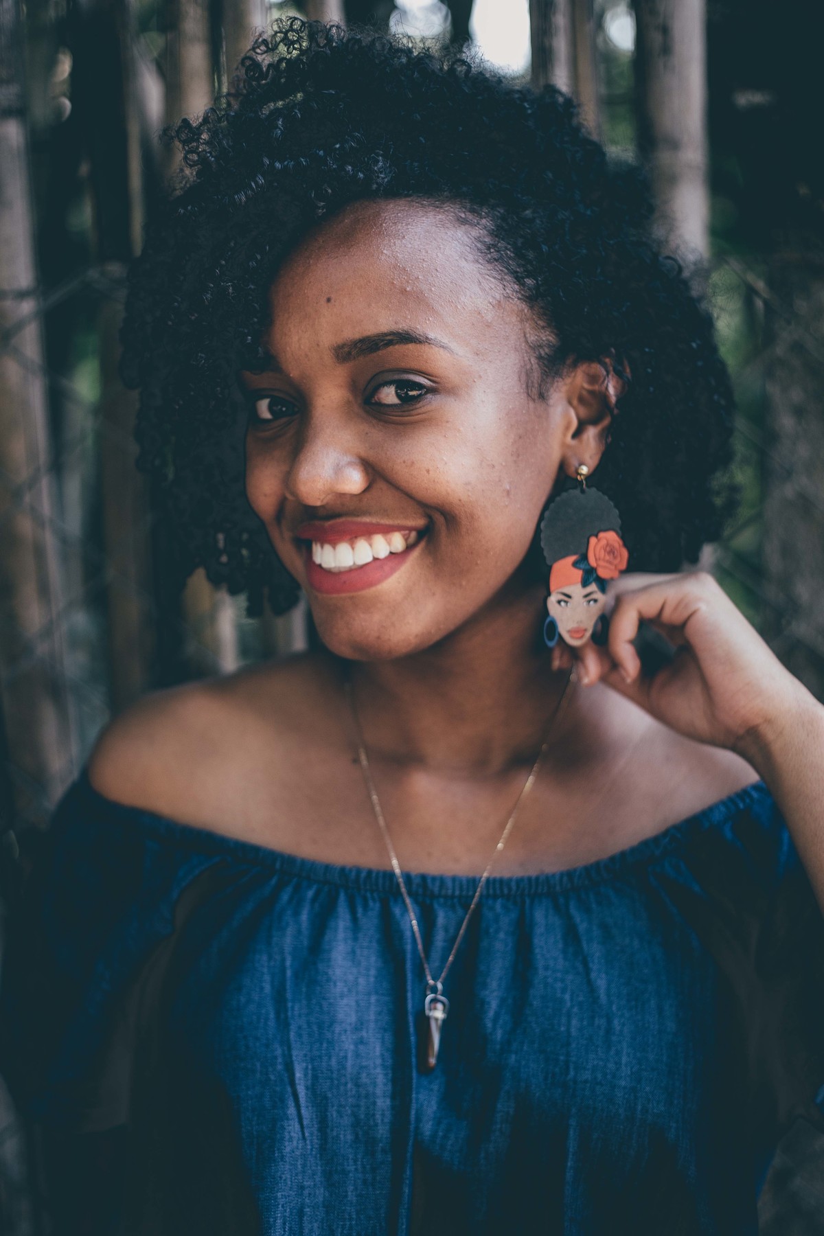 retrato feminino em que a modelo sorri para a foto e tem um belo cabelo cacheado
