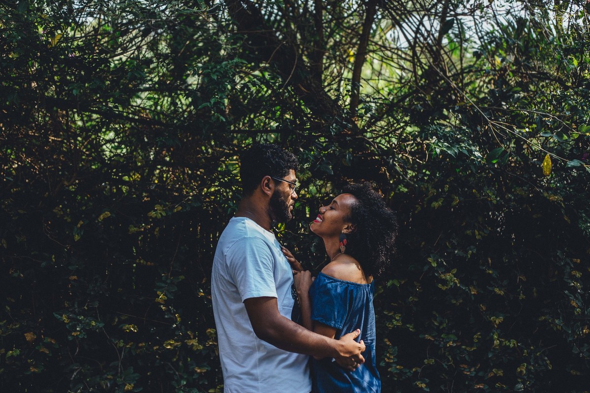 Fotografia de casal se olhando um para o outro na frente de um muro de era