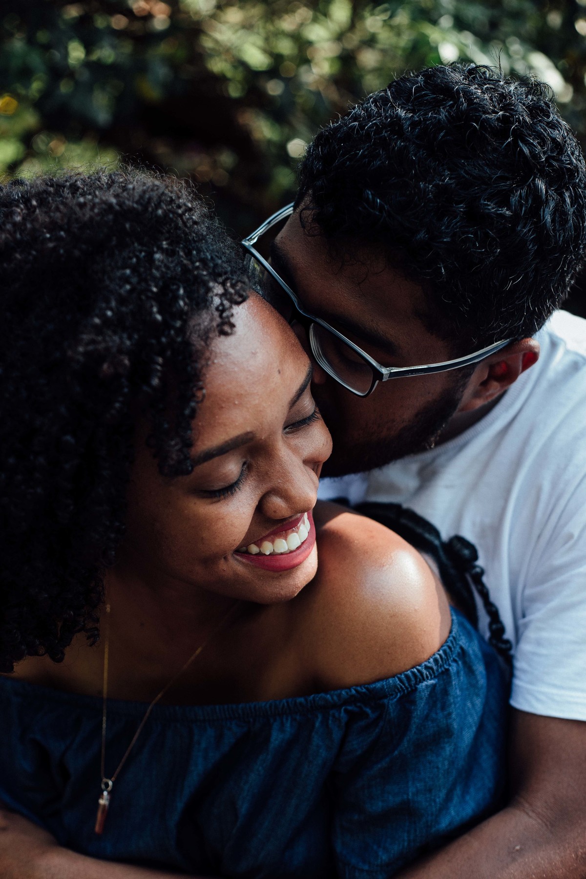 Noivo beijando o rosto de noiva enquanto ela sorri em um ensaio de save the date