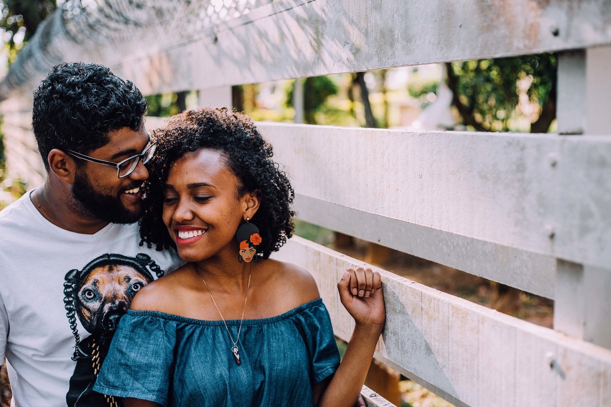 Noivo abraçando a noiva por trás e beijando o pescoço dela enquanto ela sorri