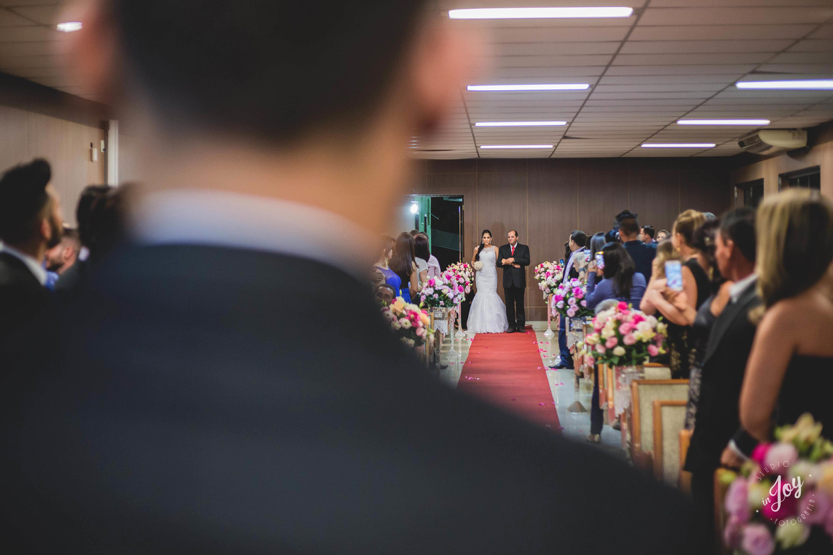 visão do noivo para a noiva que está entrando na igreja acompanhada com o pai