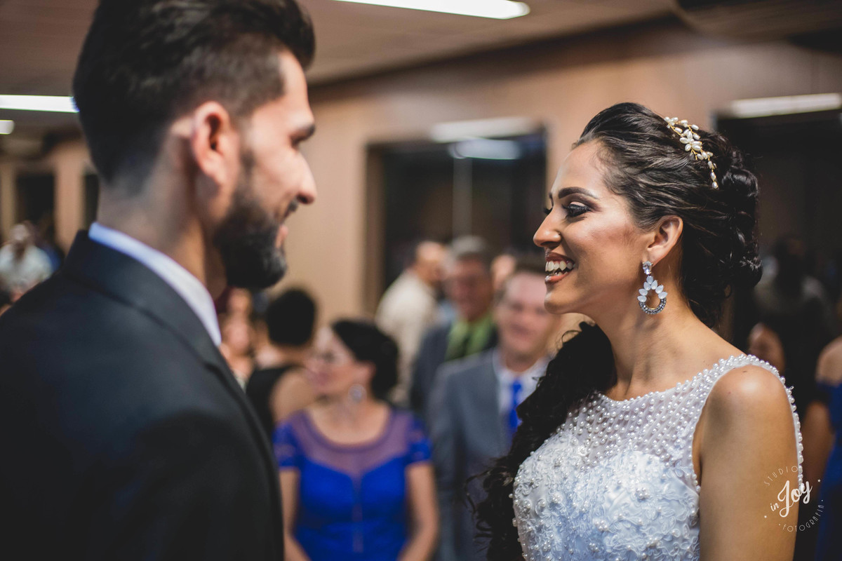 Noivos sorrindo um para o outro durante a cerimônia de casamento