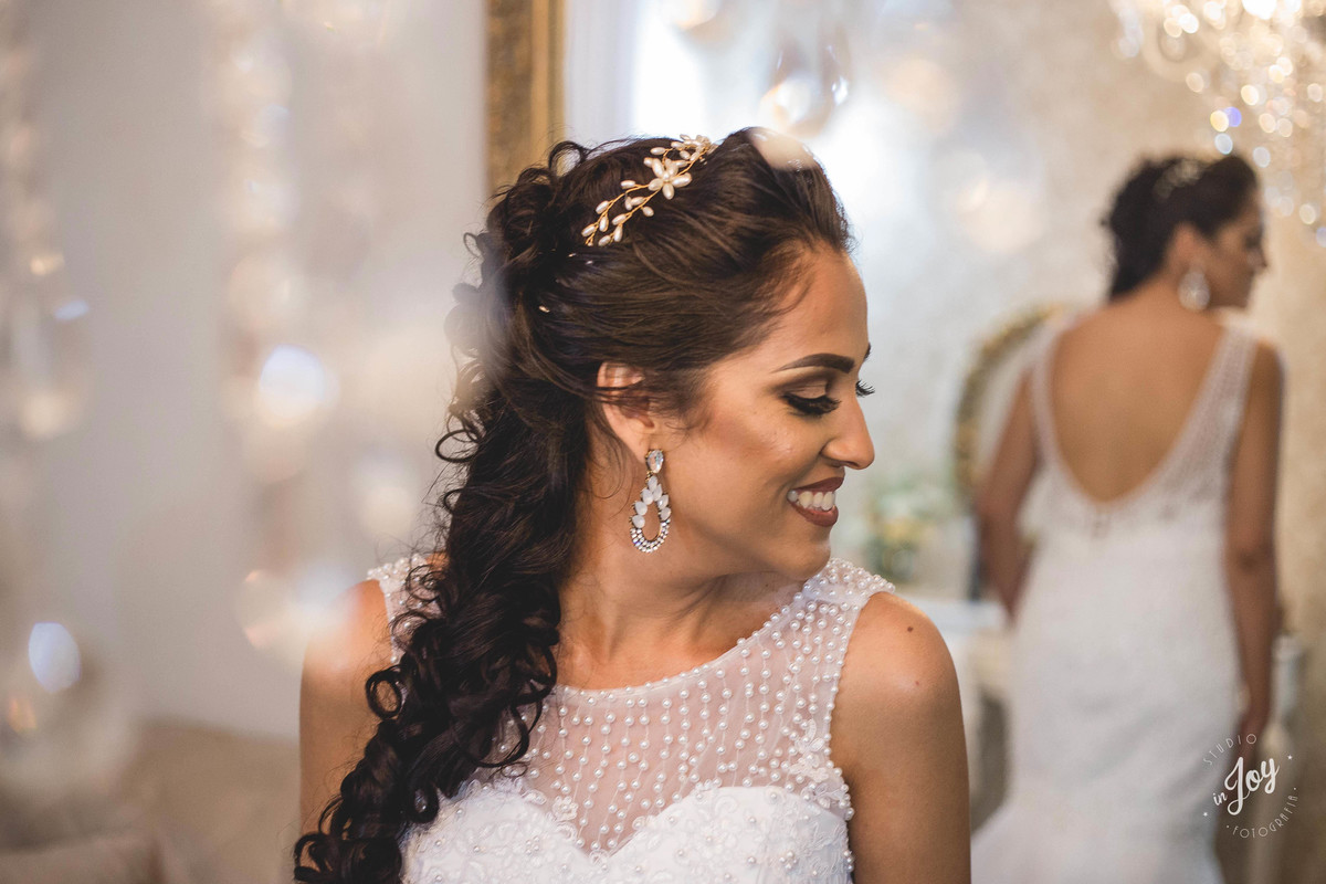 fotografia de casamento em que a noiva esta pronta se olhando no espelho e sorrindo