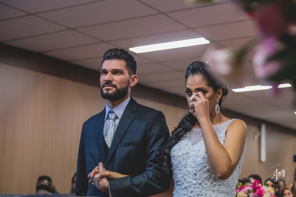 noiva chorando durante a cerimonia de casamento segurando as mãos do noivo