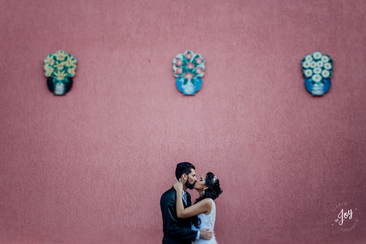 ensaio de pós casamento espaço shangrilá em Mateus Leme noivos se beijando na frente de uma parede colorida