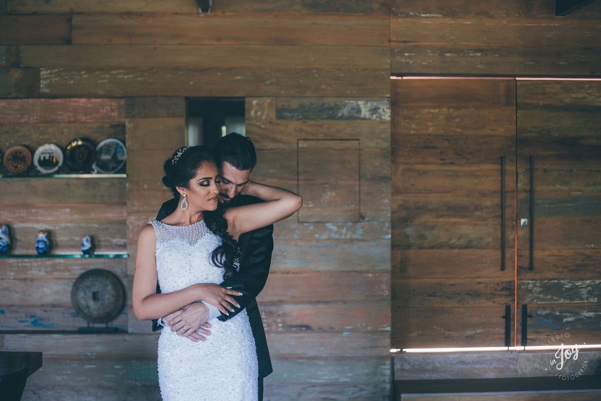 fotografia de casamento do casam que está se abraçando dentro de uma casa com detalhes de madeira