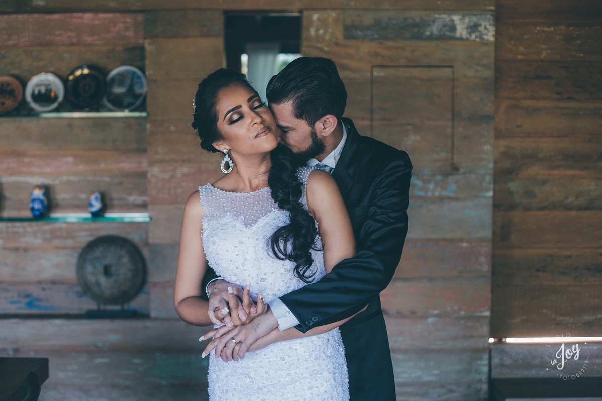 fotografia de casamento do casam que está se abraçando dentro de uma casa com detalhes de madeira